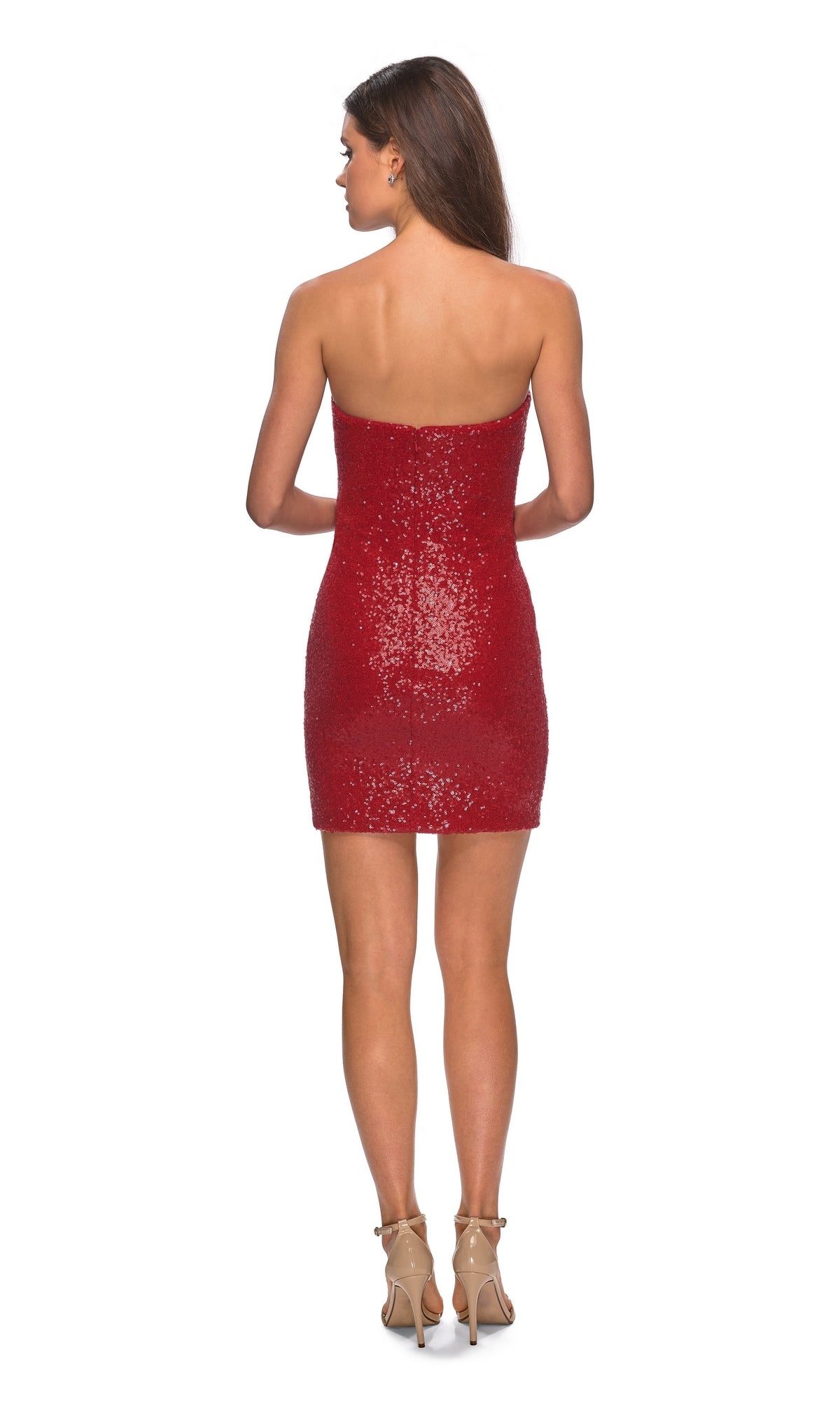 A woman stands with her back to the camera, wearing a vibrant red La Femme Short Strapless Sequin Hoco Dress 28229 and beige high heels against a plain white background.